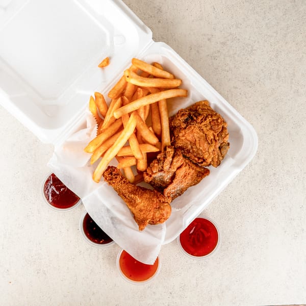 Jaws Hot Chicken & Seafood's fried chicken and fries in a takeout container with dipping sauces.
