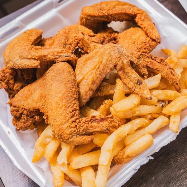 Crispy fried chicken wings and golden french fries in a white takeout container from Jaws Hot Chicken & Seafood.