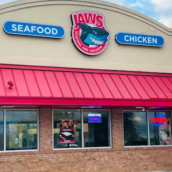 Exterior of Jaws Hot Chicken & Seafood, with a red awning and prominent shark logo.