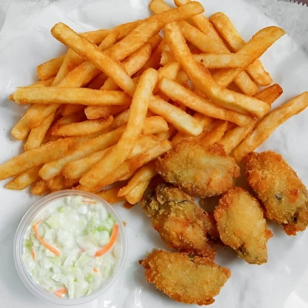 Golden french fries, crispy fried oysters, and a side of creamy coleslaw on a white paper.